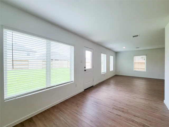 a view of an empty room with wooden floor and window