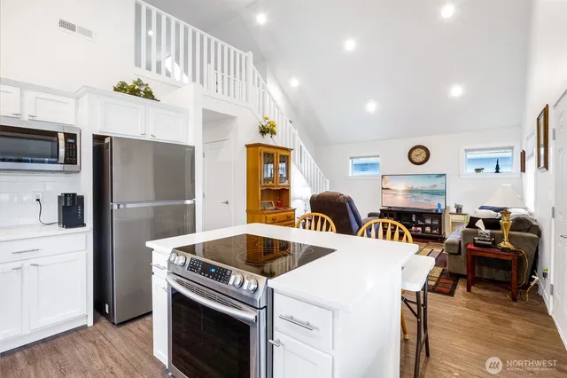 a kitchen with stainless steel appliances granite countertop a refrigerator a stove and a sink with wooden floor