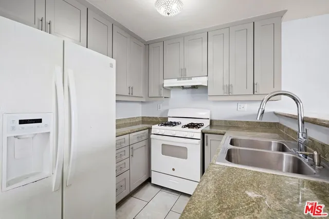 a kitchen with granite countertop white cabinets and white appliances