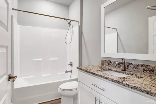 a bathroom with a granite countertop sink a toilet and a bathtub
