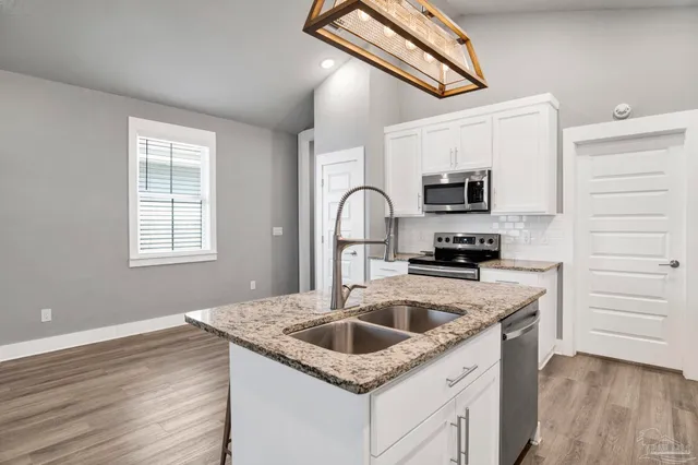 a kitchen with granite countertop a sink a stove and cabinets