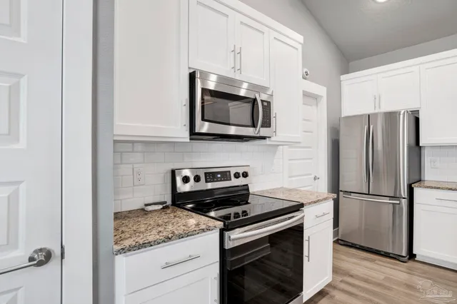 a kitchen with appliances a counter space and cabinets