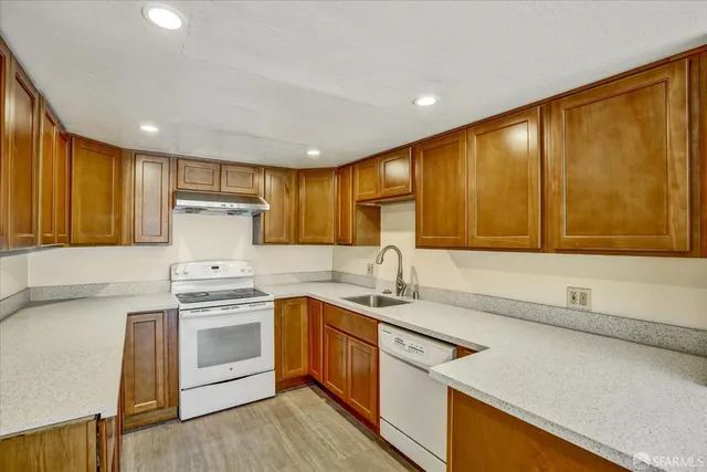 a kitchen with stainless steel appliances granite countertop a sink a stove and a refrigerator with wooden floor