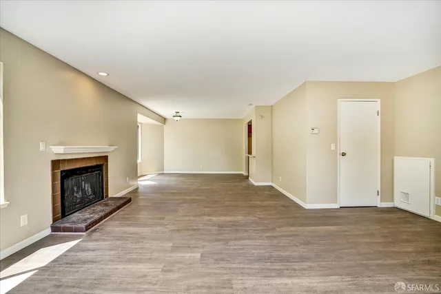 a view of empty room with wooden floor and fireplace