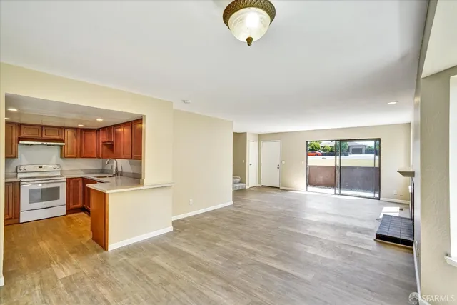 an empty room with windows fireplace and wooden floor