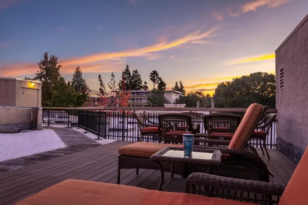 a view of a roof deck with dining table and chairs with wooden floor and fence