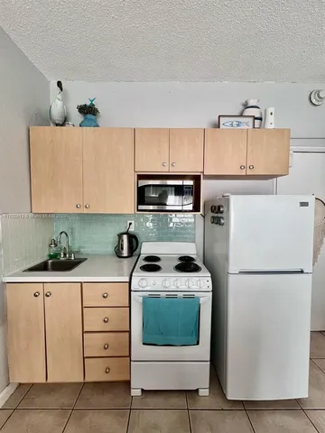 a kitchen with a refrigerator sink and cabinets