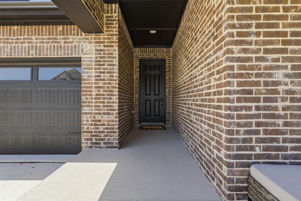 15413 Short Rdg Lane Fort Worth, TX 76008 - Photo 5 of 39 Brick facade with dark garage door, recessed entryway, and a solid black front door