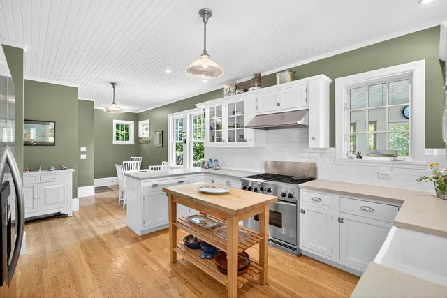 a kitchen with a stove a sink and white cabinets with wooden floor