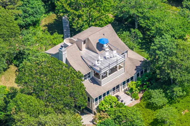an aerial view of a house with garden space and trees all around