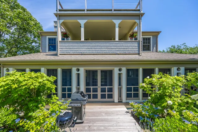 a view of a house with potted plants and a table and chairs