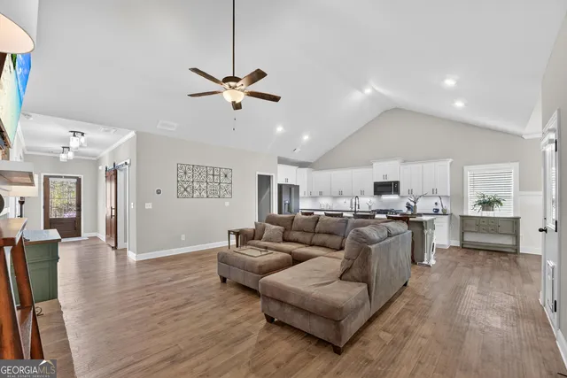 a living room with furniture kitchen view and a wooden floor