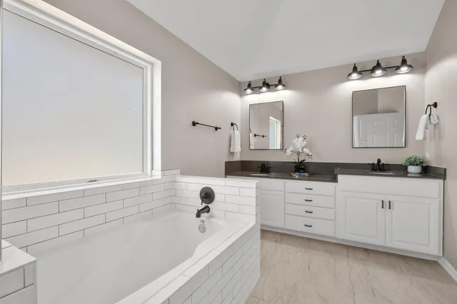 a bathroom with a bathtub sink and mirror