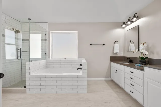 a bathroom with a bathtub a double vanity sink and mirror