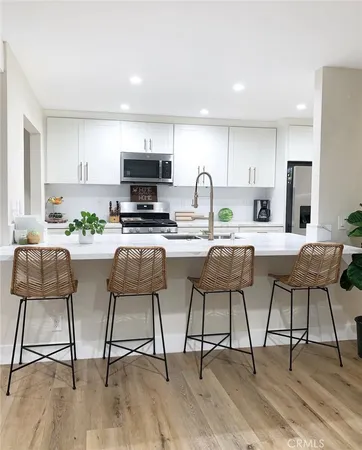 a kitchen with stainless steel appliances kitchen island granite countertop a dining table chairs and a refrigerator