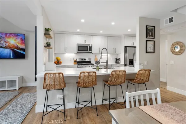 a kitchen with stainless steel appliances kitchen island granite countertop a dining table chairs and a refrigerator