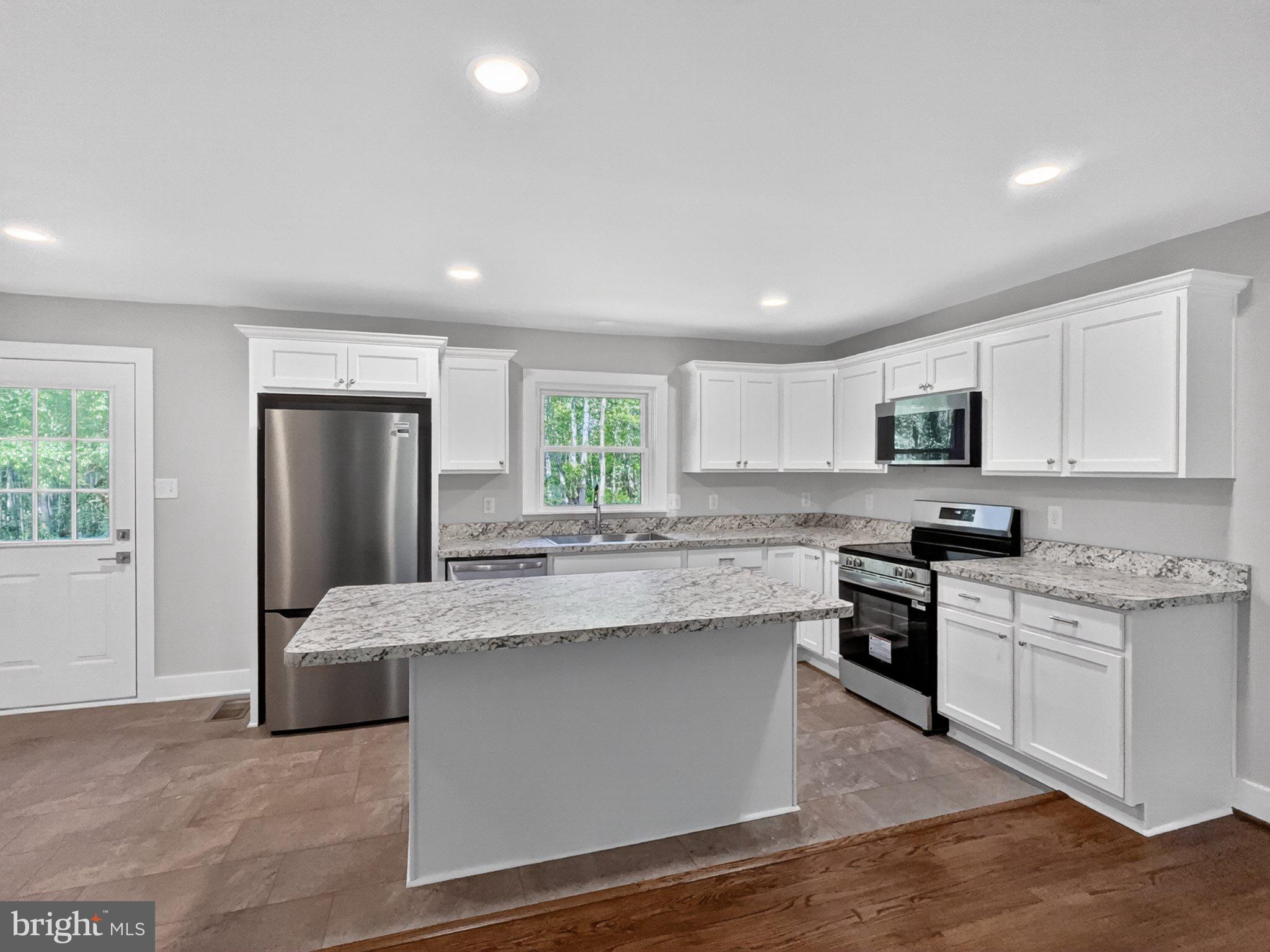 5408 Towles Mill Road Partlow, VA 22534 - Photo 12 of 24 a large kitchen with stainless steel appliances granite countertop a stove a sink dishwasher and a refrigerator with wooden floor