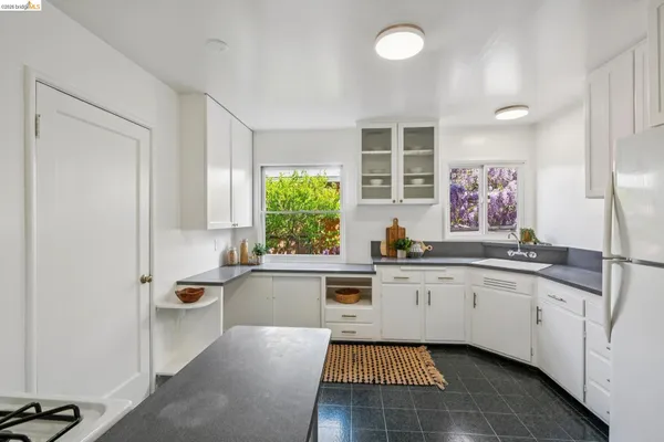 a large kitchen with granite countertop a sink and white cabinets