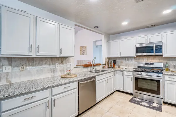 a kitchen with granite countertop white cabinets stainless steel appliances and a sink