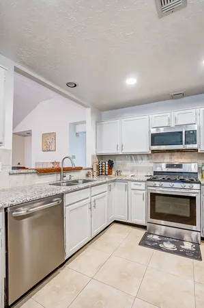 a kitchen with granite countertop stainless steel appliances a stove sink and cabinets
