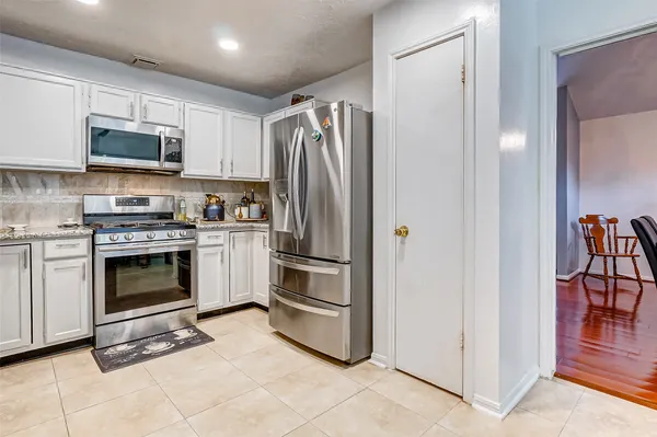 a kitchen with stainless steel appliances white cabinets and a stove top oven