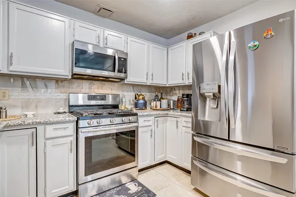 a kitchen with stainless steel appliances white cabinets white stove a microwave and a refrigerator