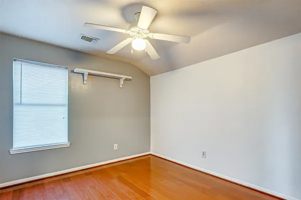 an empty room with a ceiling fan and wooden floor