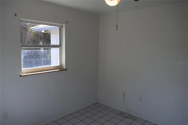 a view of an empty room with window ceiling fan and windows
