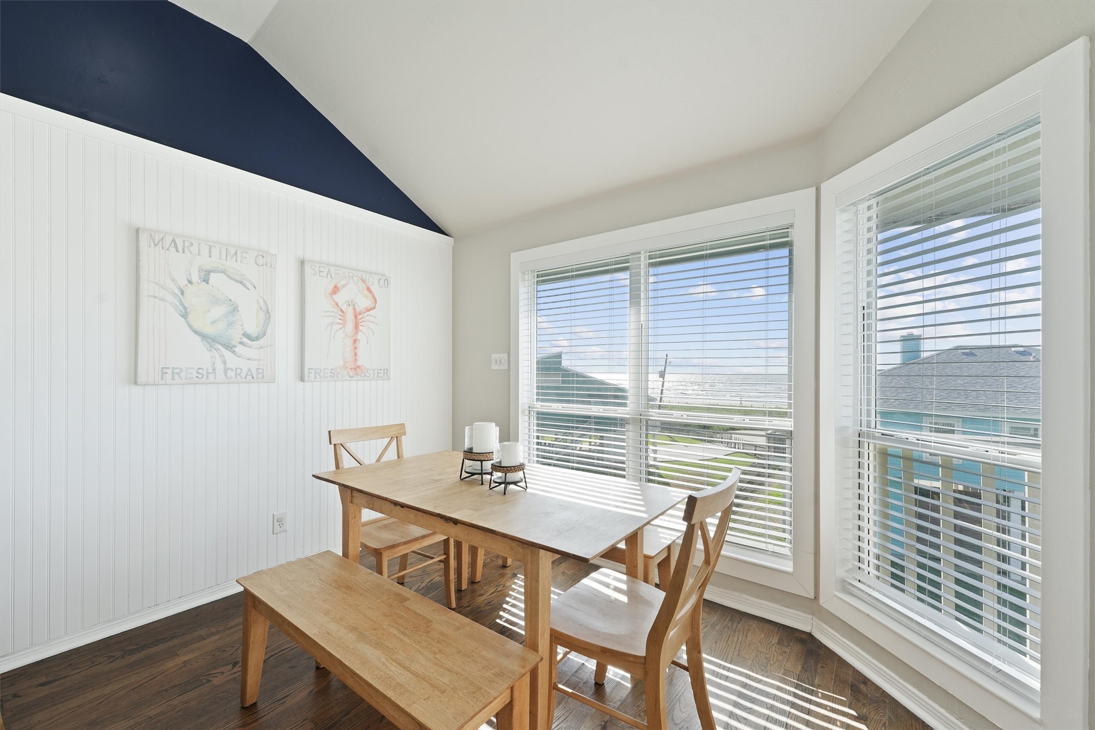 17607 Termini-San Luis Pass Road Galveston, TX 77554 - Photo 18 of 42 Large windows fill the dining area with natural light, offering scenic views while enjoying a meal. The navy accent wall and coastal-themed artwork add character and warmth to the space.
