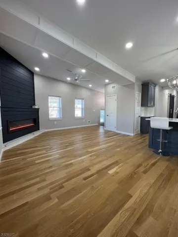 a view of an empty room with kitchen and window