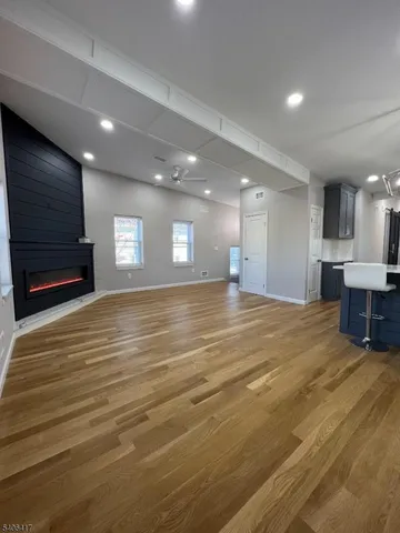 a view of kitchen and empty room with wooden floor and fan