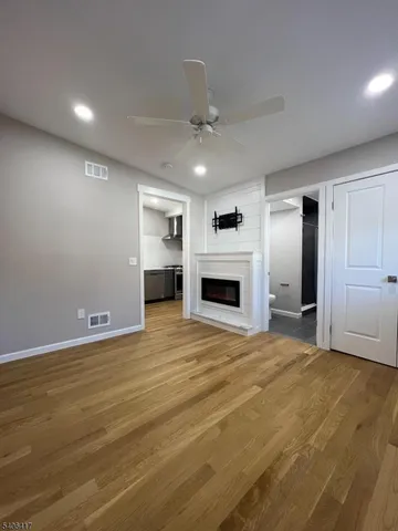 a view of empty room with kitchen and fireplace