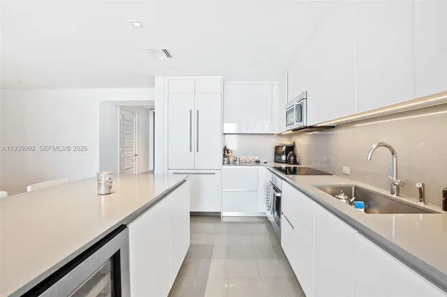 a kitchen with a sink dishwasher and white cabinets with wooden floor