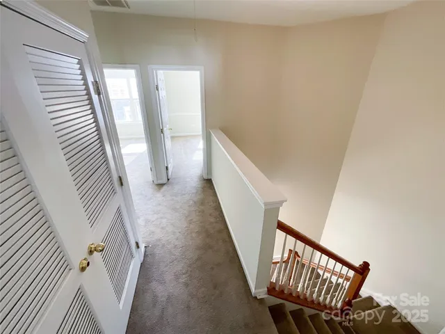 an empty room with chandelier fan and windows