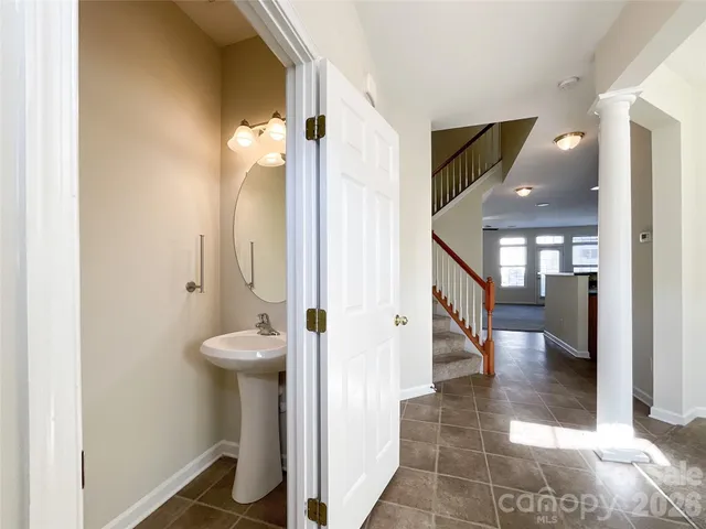 a view of a hallway with wooden floor and a bathroom
