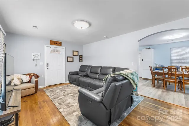 a living room with furniture and a dining table with wooden floor
