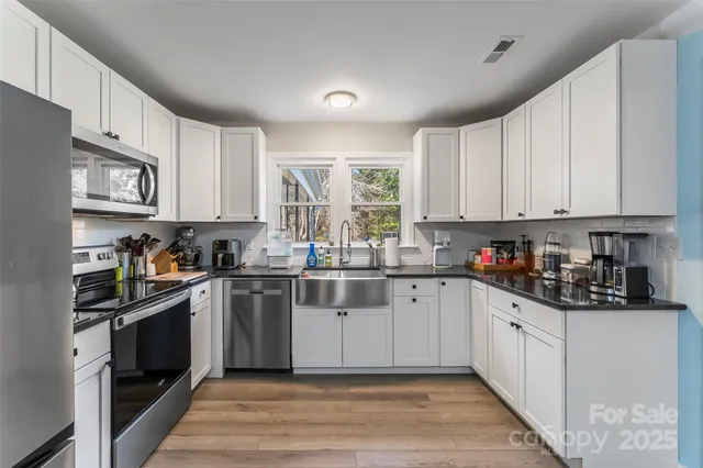 a kitchen with stainless steel appliances granite countertop a stove a sink and white cabinets