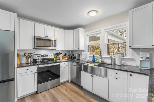 a kitchen with granite countertop white cabinets a sink a window and stainless steel appliances
