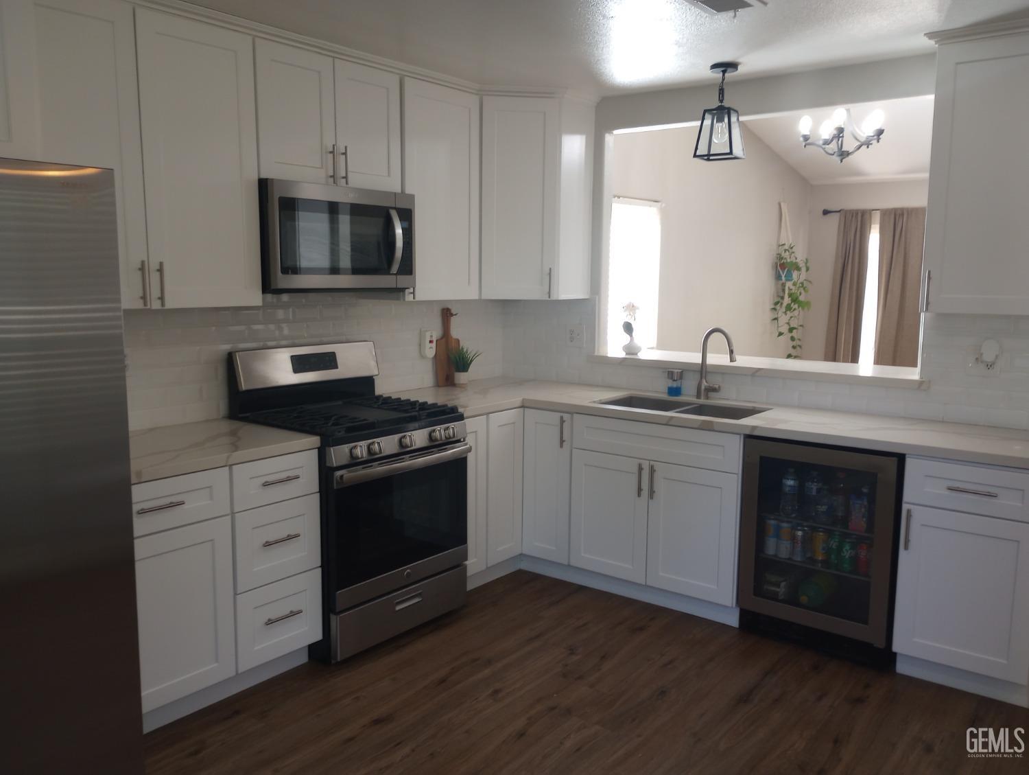 Undisclosed Address Bakersfield, CA 93313 - Photo 4 of 18 a kitchen with cabinets stainless steel appliances a sink and wooden floor
