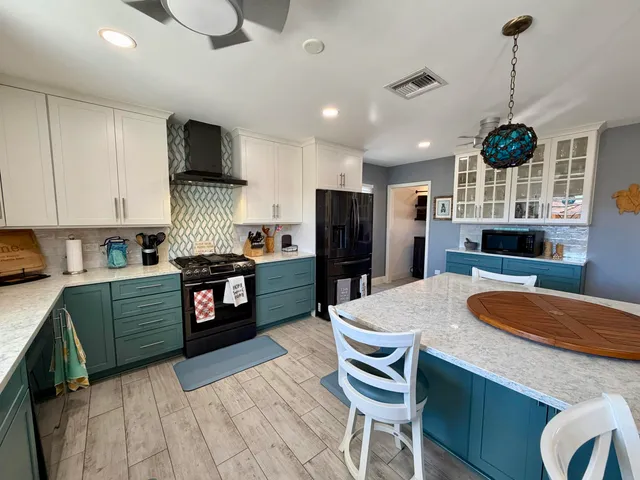 a kitchen with stainless steel appliances kitchen island granite countertop a sink a stove a refrigerator cabinets and chairs