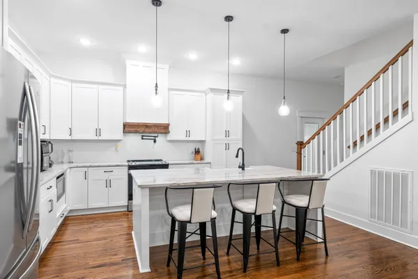a kitchen with stainless steel appliances granite countertop a sink a stove and a wooden floors