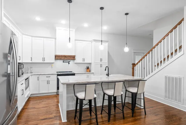 a kitchen with stainless steel appliances granite countertop a sink a stove and a wooden floors