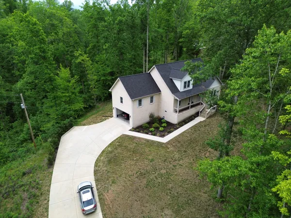 an aerial view of residential house with outdoor space and trees all around