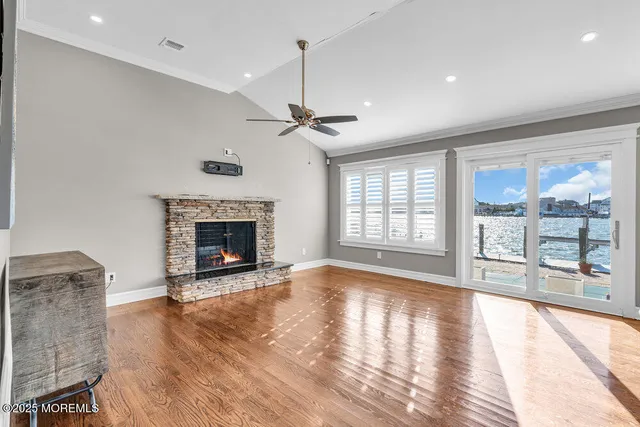 a view of an empty room with wooden floor and a fireplace