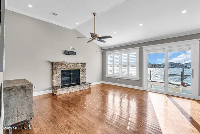 a view of an empty room with wooden floor and a fireplace