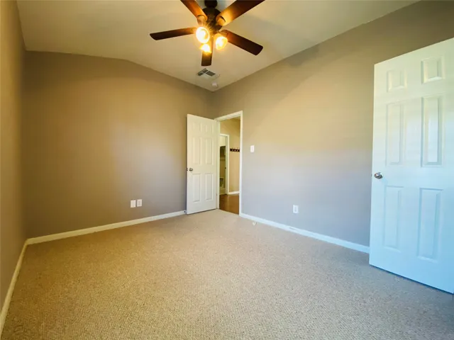 an empty room with a chandelier fan and a ceiling fan