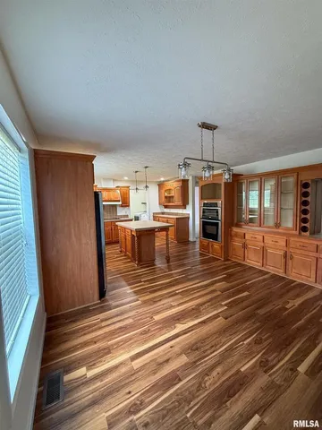 a room with stainless steel appliances wooden floor and chandelier