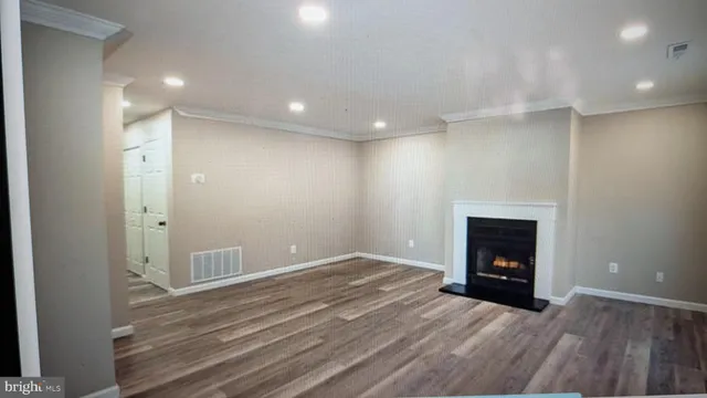a view of an empty room with wooden floor fireplace and a window