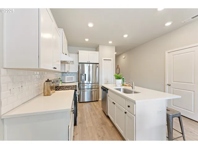 a kitchen with a sink a stove a refrigerator and white cabinets