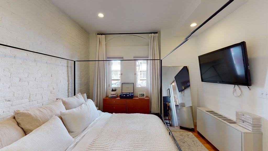 27 Bowdoin Street, Unit 1B Boston, MA 02114 - Photo 13 of 18 a bedroom with a bed a flat screen tv and a couch